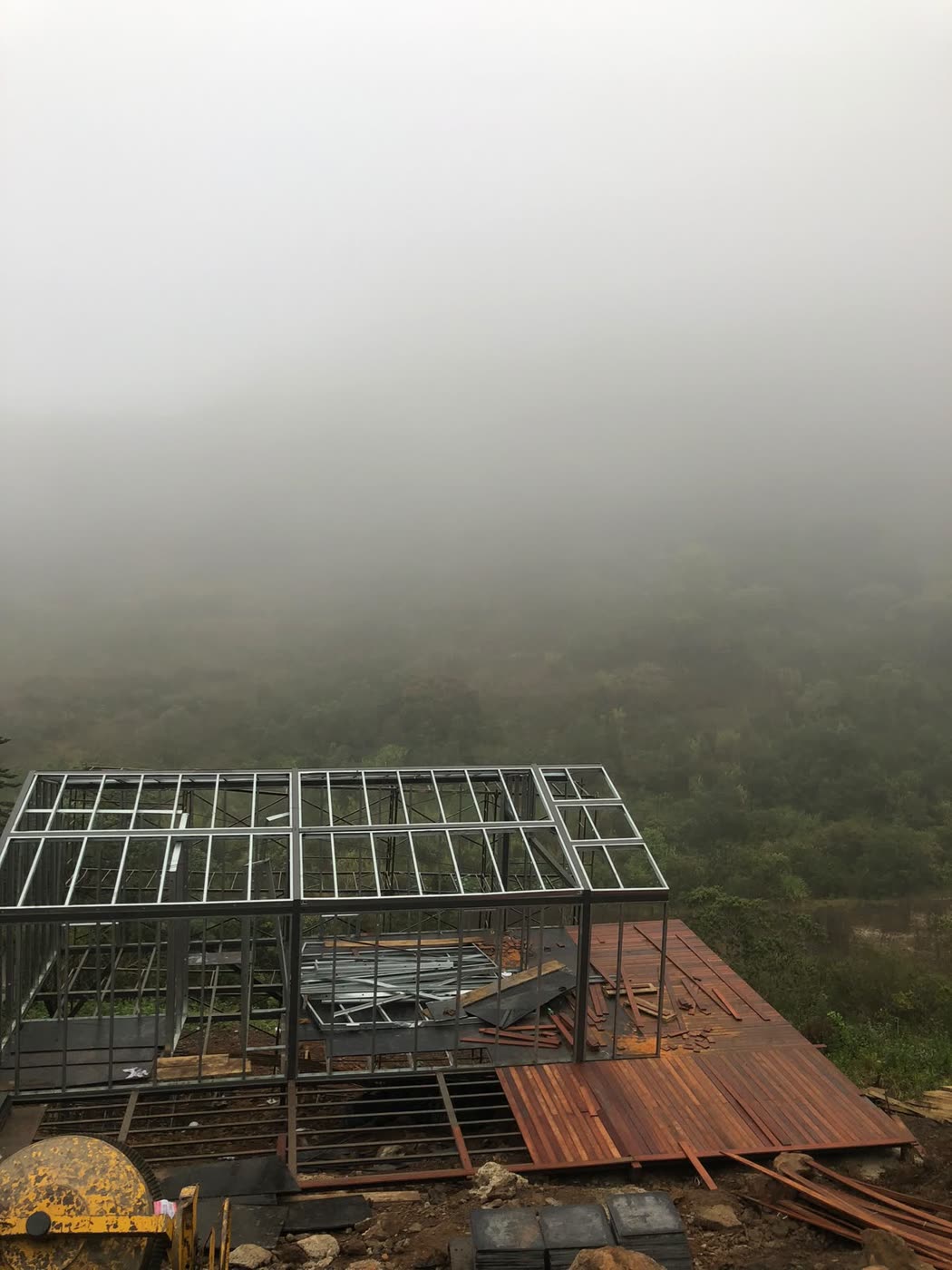 Estrutura de uma casa em metalon na encosta de um morro, com neblina