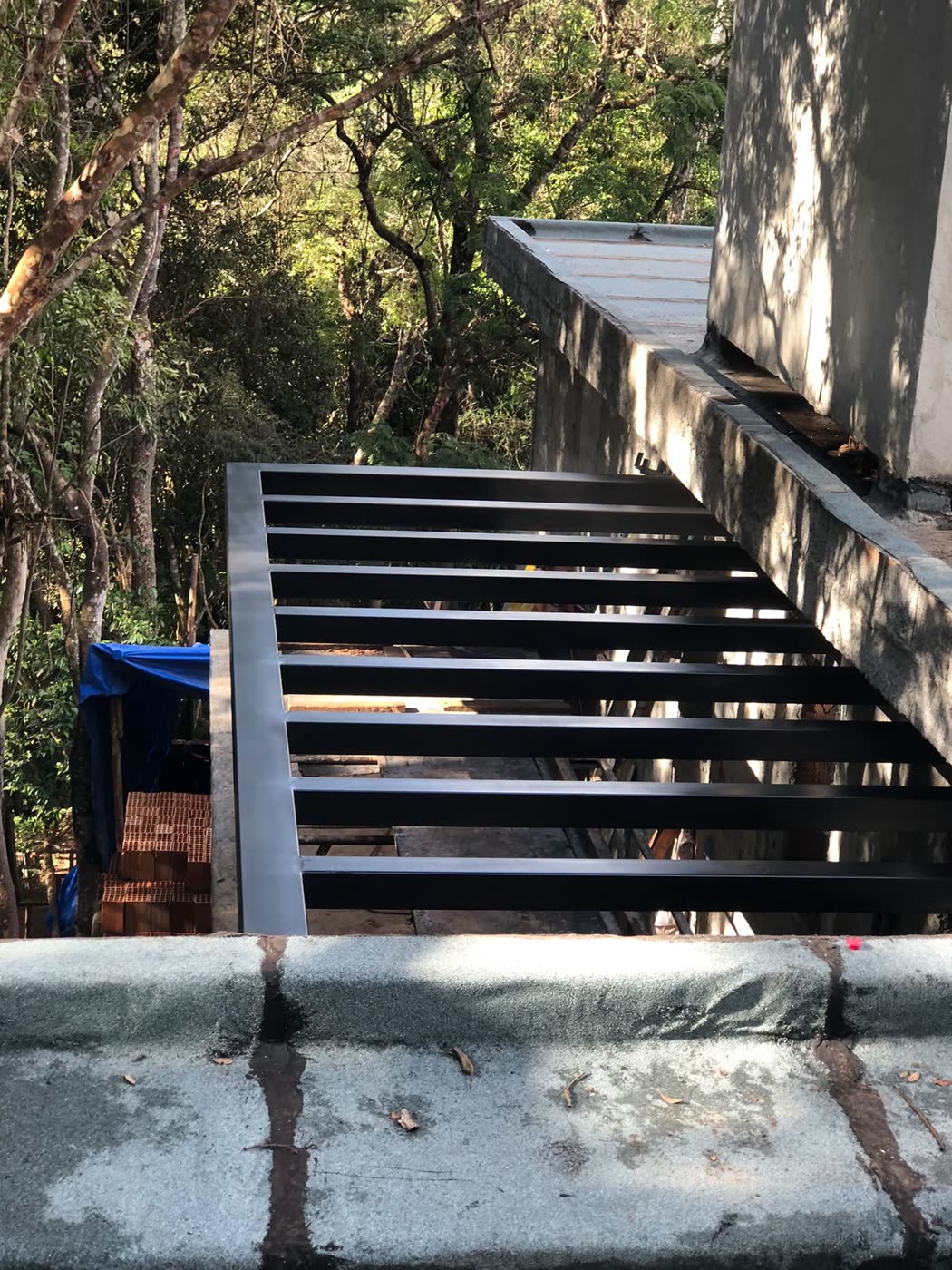 Pergolado de tubos de aço preto preso à casa